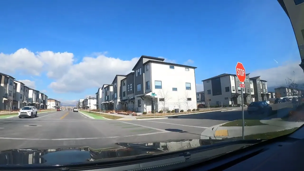Street view of modern townhomes on both sides of the road with a stop sign in American Fork