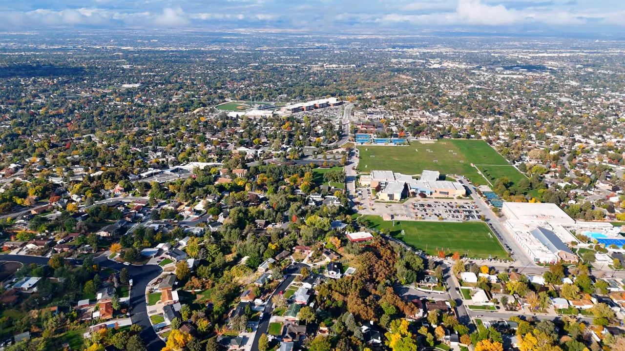 High-resolution aerial view of a suburban area with many homes, streets, parks and a school complex.